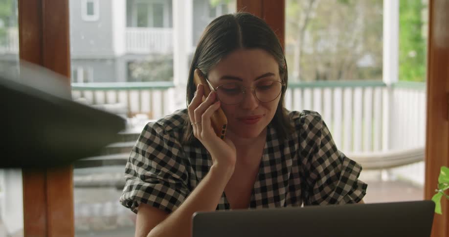 Woman working on a laptop talking on the phone at home