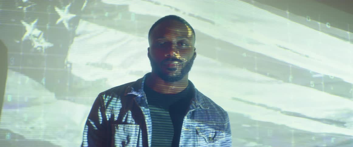 A man is posing in front of a projector screen