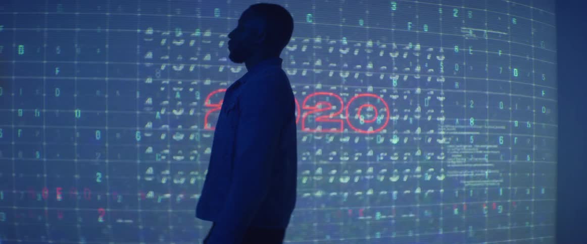A man is posing in front of a projector display