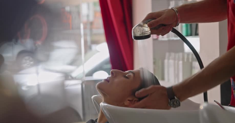 A female getting her hair washing in a sink by a male in a hair salon