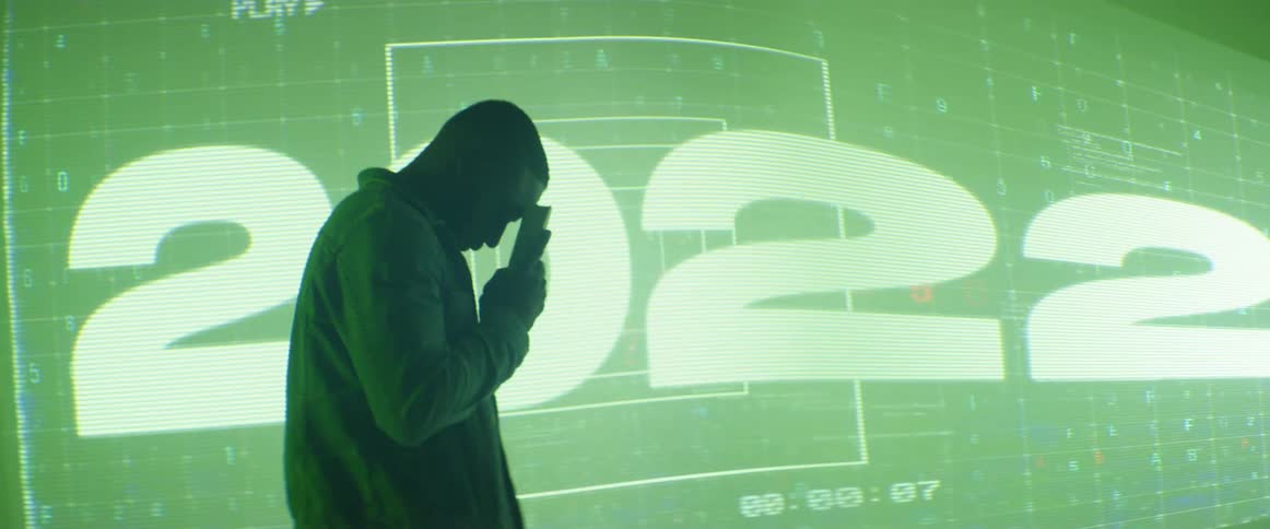 A silhouette of a man holding up a book to his head with a screen in the background