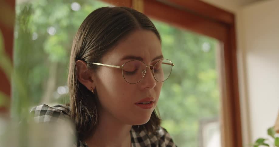 A woman sits at home worried as she looks at something