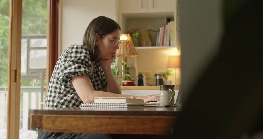 A teenage girl does school work on her laptop at home