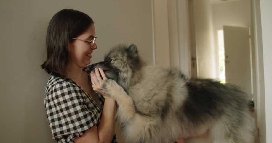 A woman playing with her dog inside