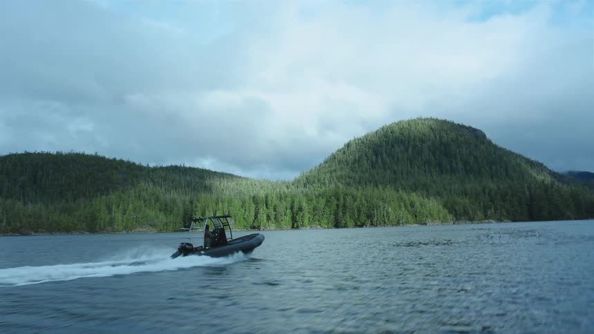 Inflatable boat navigating on a lake near the pine forests on the mountains