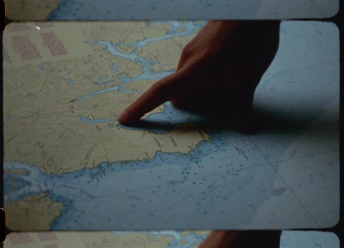 A person pointing at a map with a finger caught on vintage film