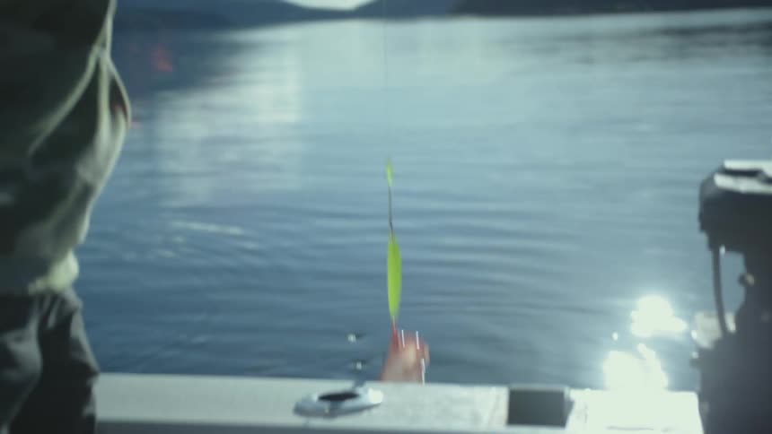 A man catches a fish and pulls it up on the boat