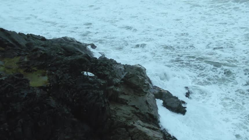 An aerial view of waves crashing on a cliff