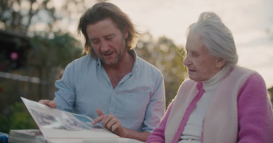 A man looks over a photo album with his mother