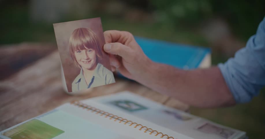 A man is holding a photo of a boy from a photo album