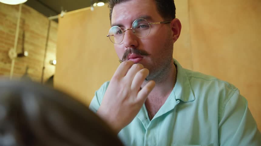 A man combing a mustache in a mirror