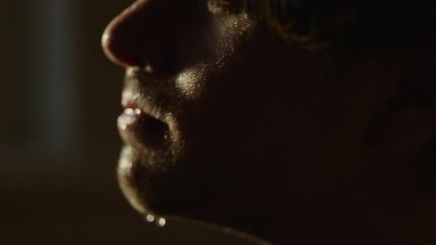 A man in a room splashing water on his face with a wall in the background