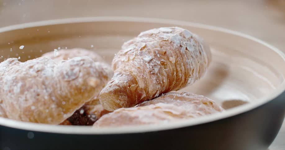 Croissant pastries falling into a bowl on a table