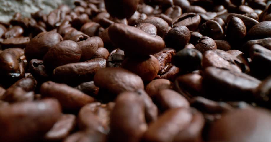 Brown roasted coffee beans rolling towards the camera