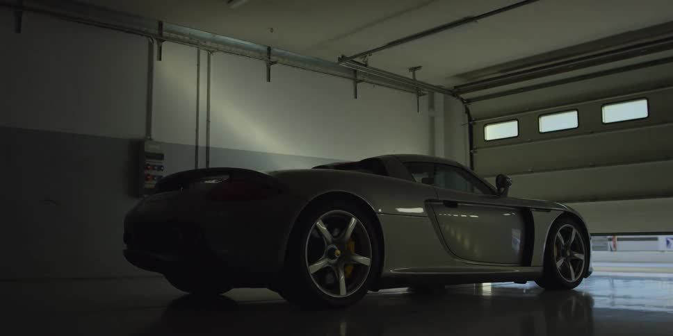 A sports car sits in a garage as the door opens