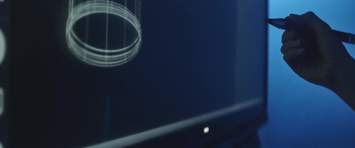 Designer drawing over an interactive screen in a dimly lit room