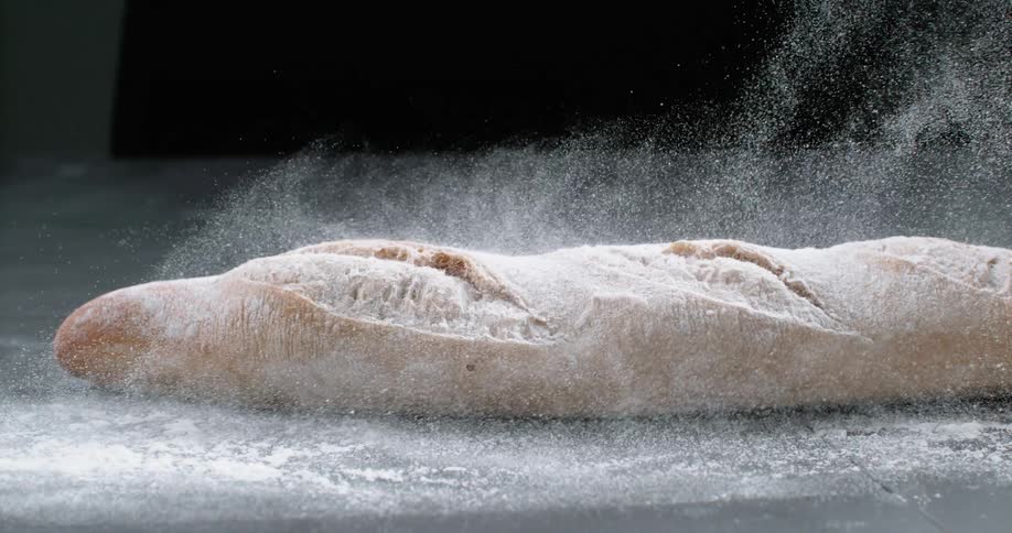Baguette bread dough being sprinkled with flour