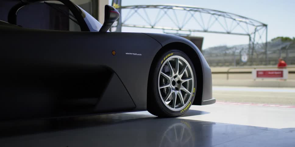 A man walking around a luxury sports car parked in a garage