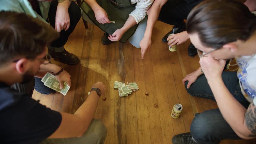 A group of friends gambling on a game of dice on the floor of the living room