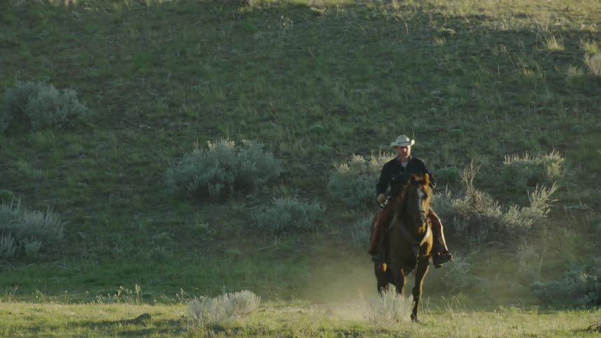 A cowboy rides his brown horse directly towards camera at sunset in a shot that evokes feelings of nostalgia, freedom and possibility