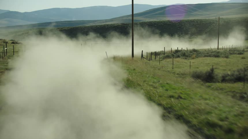 Large dust plumes are kicked up from the Cowboys pickup truck on the way to tending to bison in rural Montana