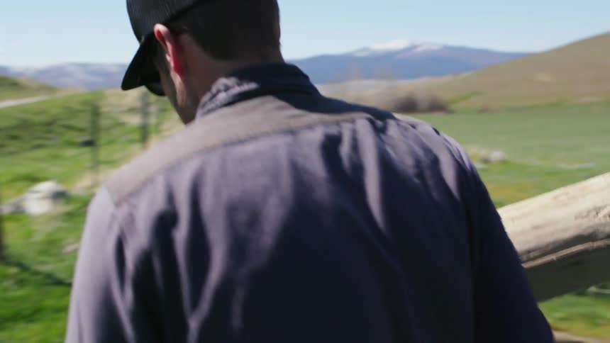 Two Montana ranchers carry fence posts and stack them at a rural ranch in Montana