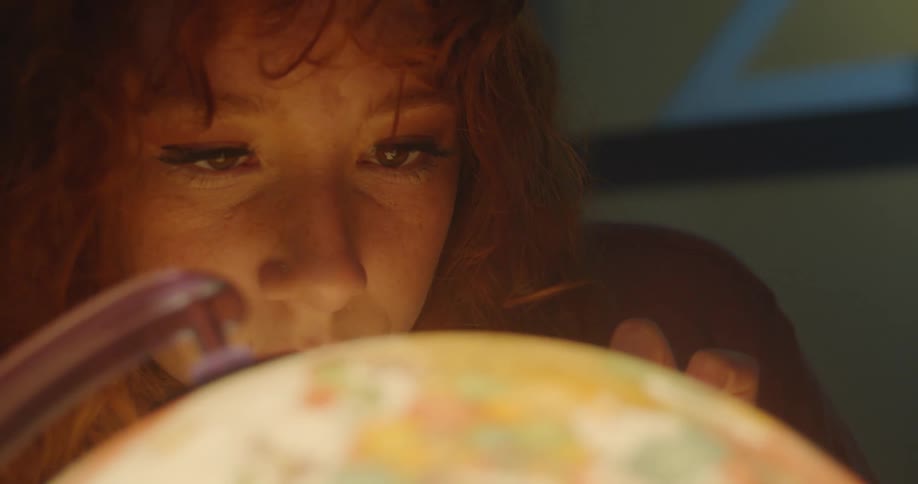 A teenage girl looks at a globe