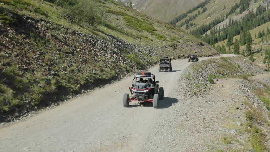 Off road vehicles drive in line on the mountain trail