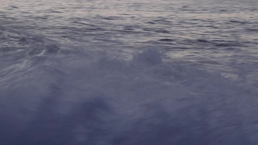An ocean with waves of water with the sky and clouds in the background