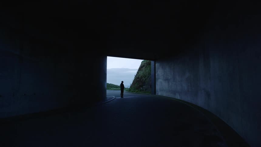 Silhouette of a man walking back and forth on the entrance of a tunnel