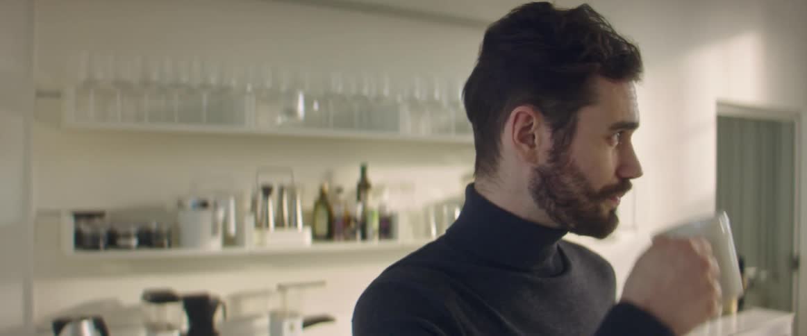 Bearded young man drinking a hot beverage at home