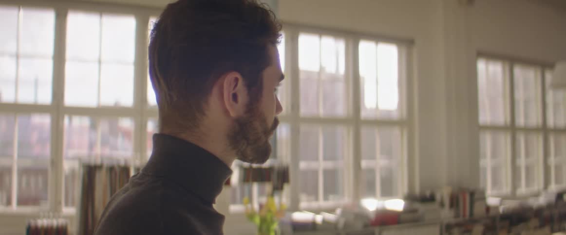 Young bearded man drinking coffee in the office kitchen