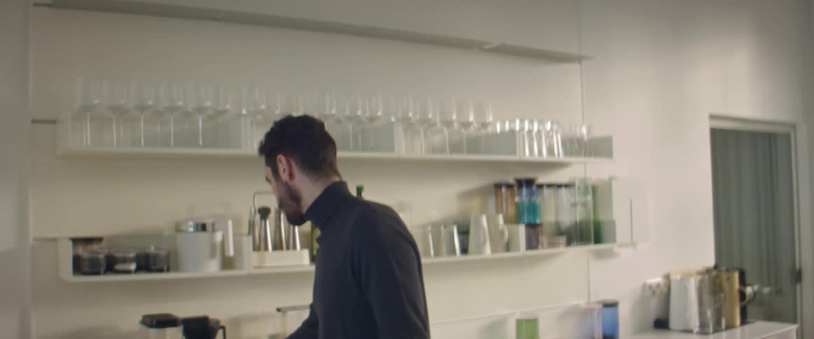 A man stands in a kitchen and drinks from a mug
