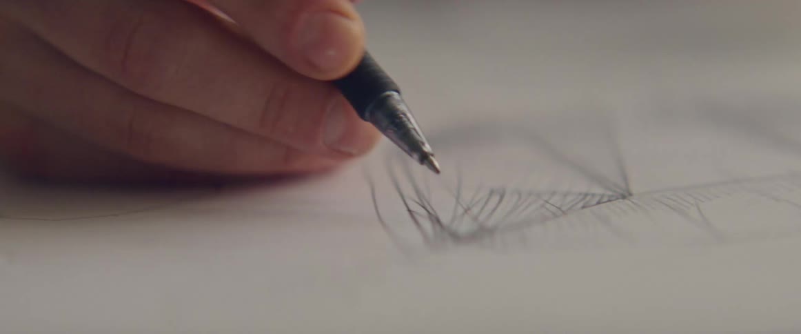 A person in a room drawing on a paper with a pen