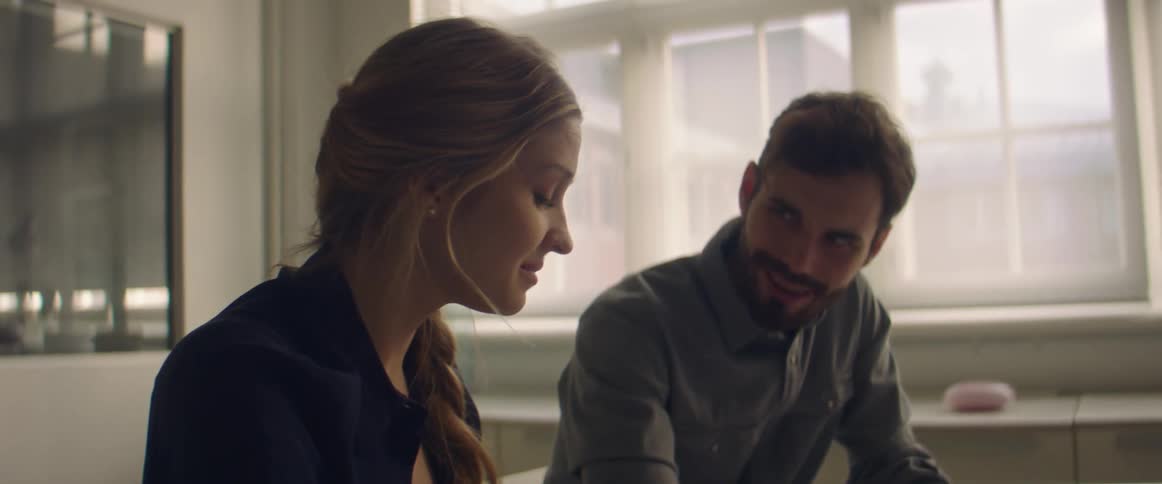A man and woman sit at a table together talking about the papers in front of them