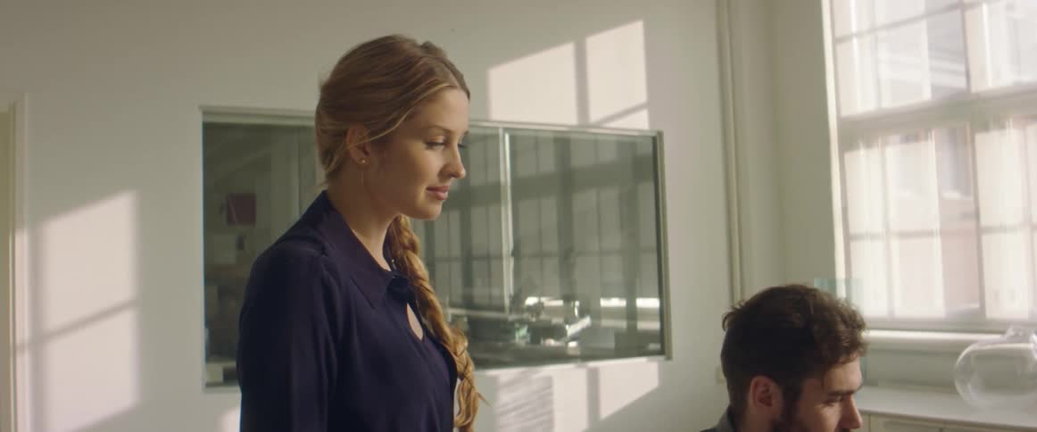 A woman and a man in a room with a wall and window in the background