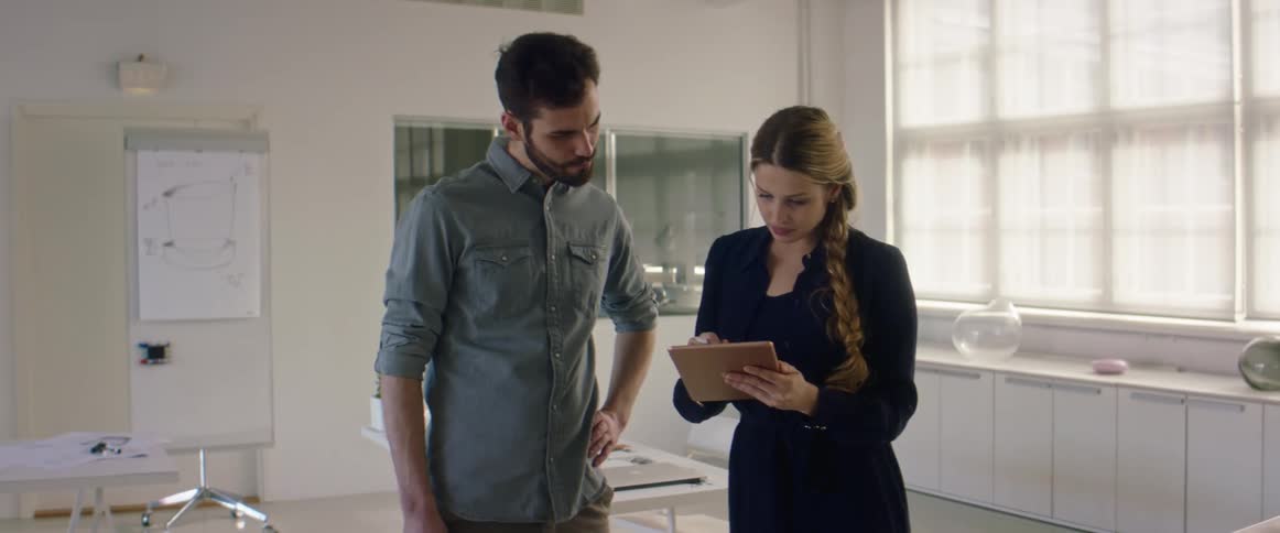 Two coworkers collaborating while standing in an office space