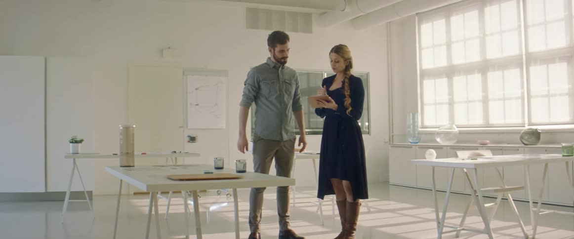 A man and a woman in a room looking at a tablet with a wall in the background