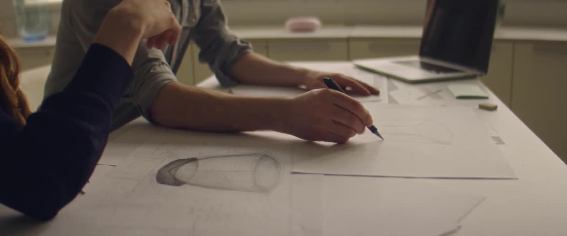 A man and woman sketch professionally on a piece of paper