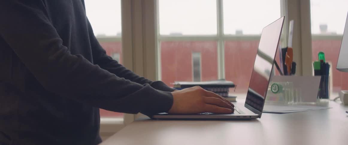 A person in a room placing a laptop on a counter with a window in the background
