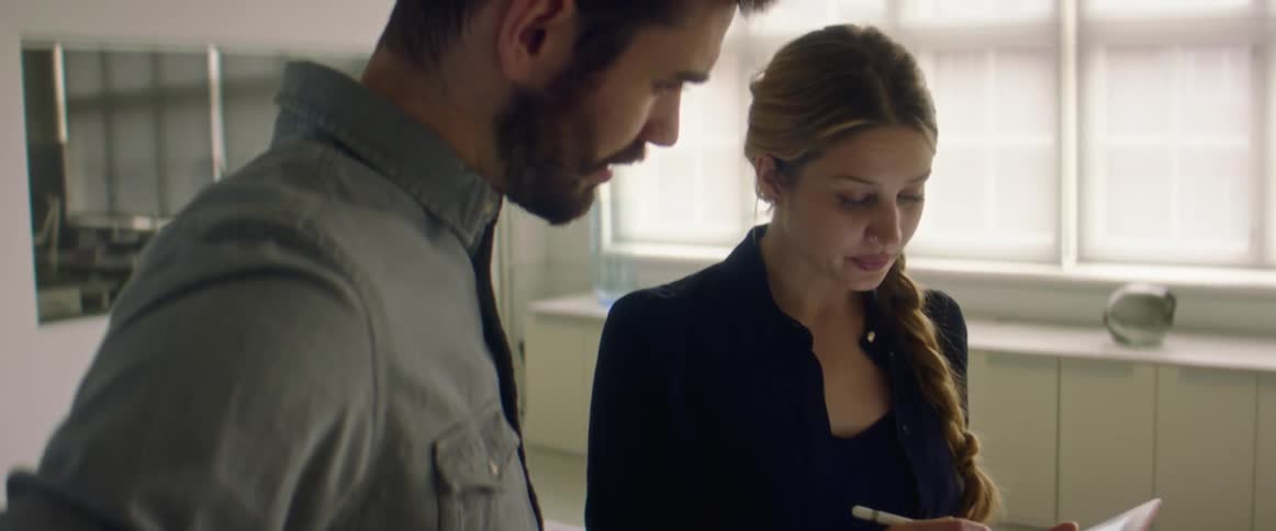 A woman in an office shows a drawing on a tablet to a coworker