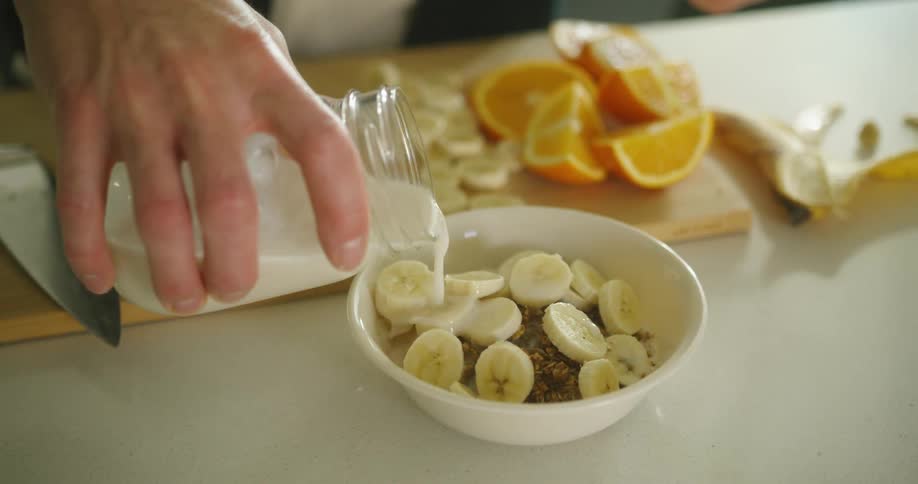 A person pouring milk into a bowl of food