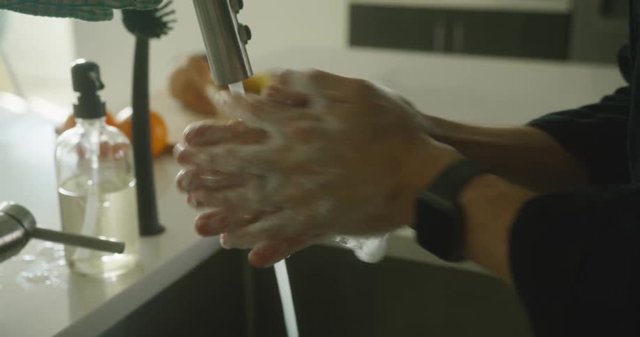 A person washing his hands with soap on the kitchen sink