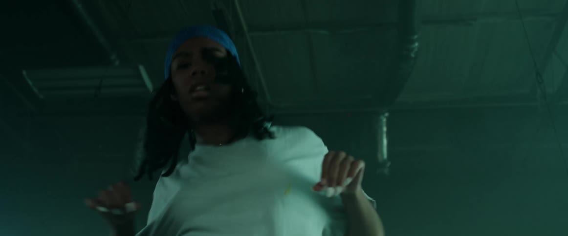 Woman with a headband braids and a white loose t shirt dances in a dark room with lights