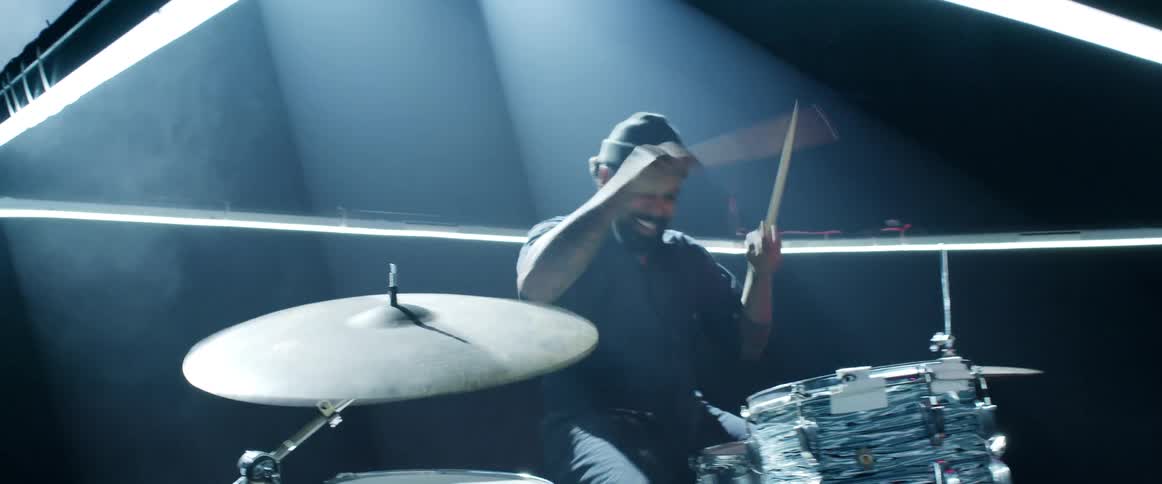 A man is playing drums on the dark stage