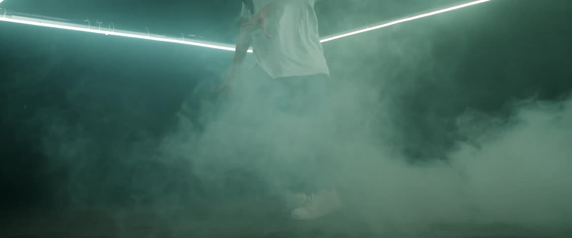 Young woman energetically dancing inside a ring of green lights inside a dark room
