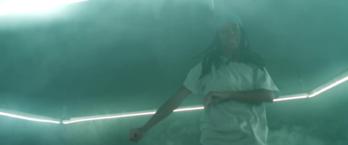 Woman dances in foggy room lit by long neon light