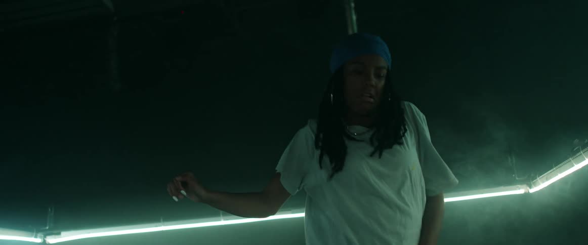 A girl with a bandanna and earrings dancing in a room