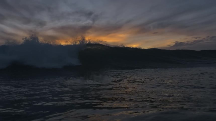 Waves in rough water under a colorful orange sky