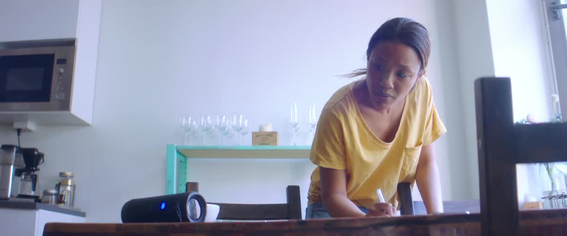 A woman writing on a table in a kitchen